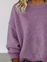 Woman wearing a purple round neck dropped shoulder sweater with dark-wash jeans.