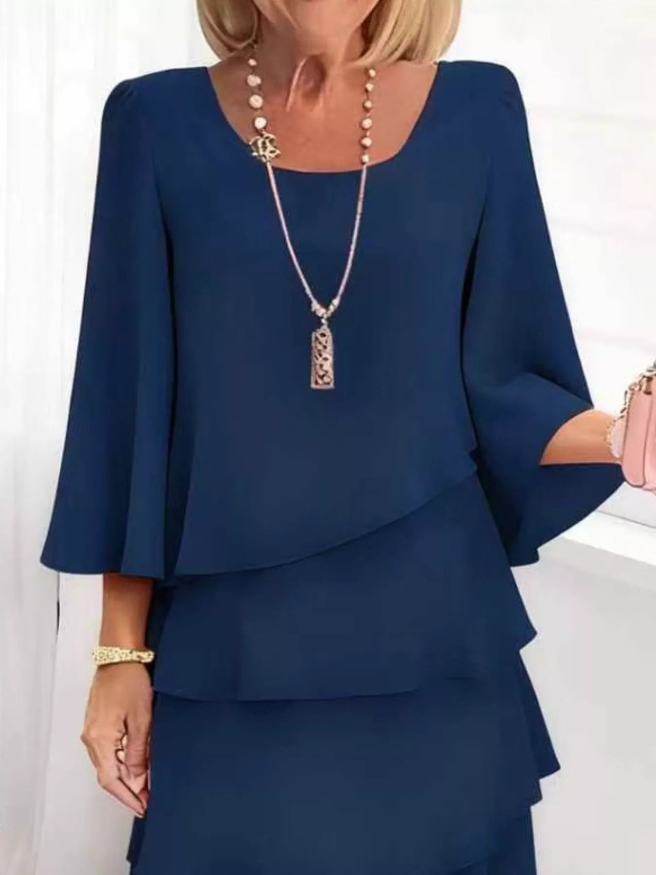 Woman wearing a blue outfit with a necklace against a white background