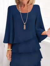 Woman wearing a blue outfit with a necklace against a white background