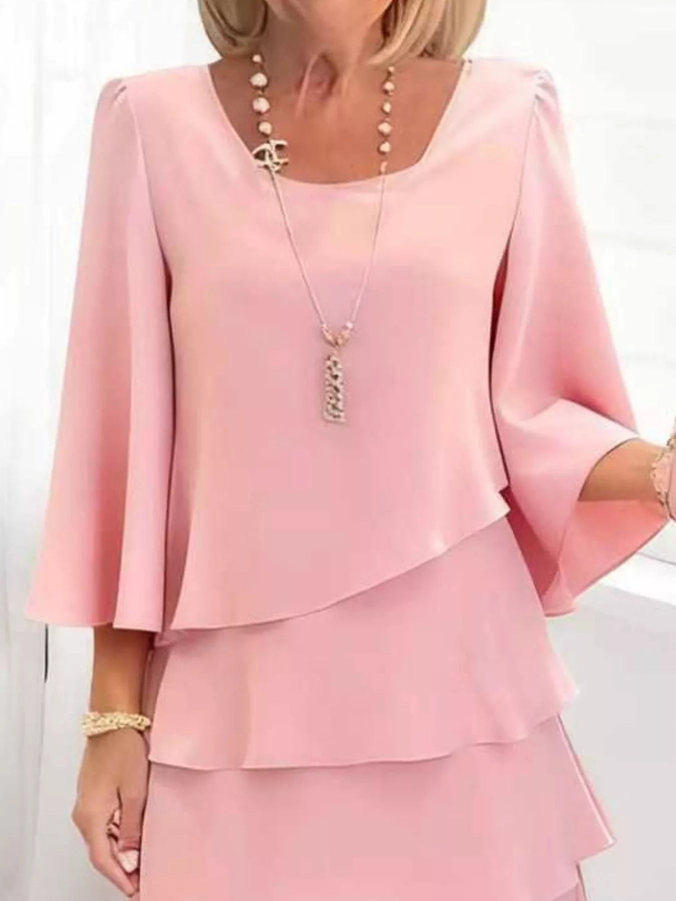 Pink dress with layered skirt and three-quarter sleeves on a white background
