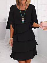 Woman wearing a black layered dress with a white background