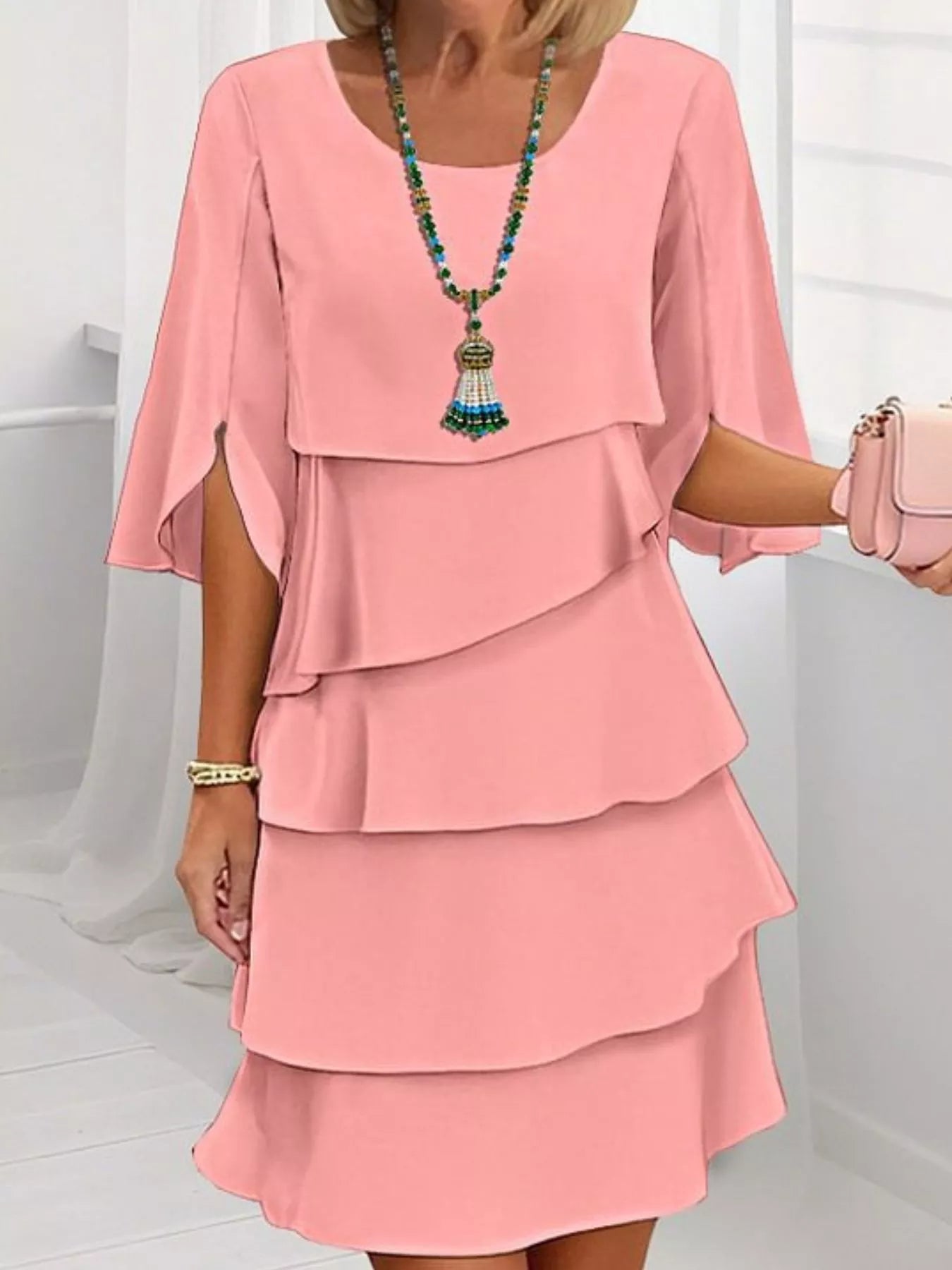 Woman wearing a coral layered dress with a white background
