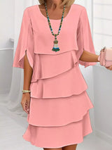 Woman wearing a coral layered dress with a white background