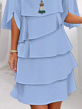 Light blue layered dress with a decorative brooch on a white background