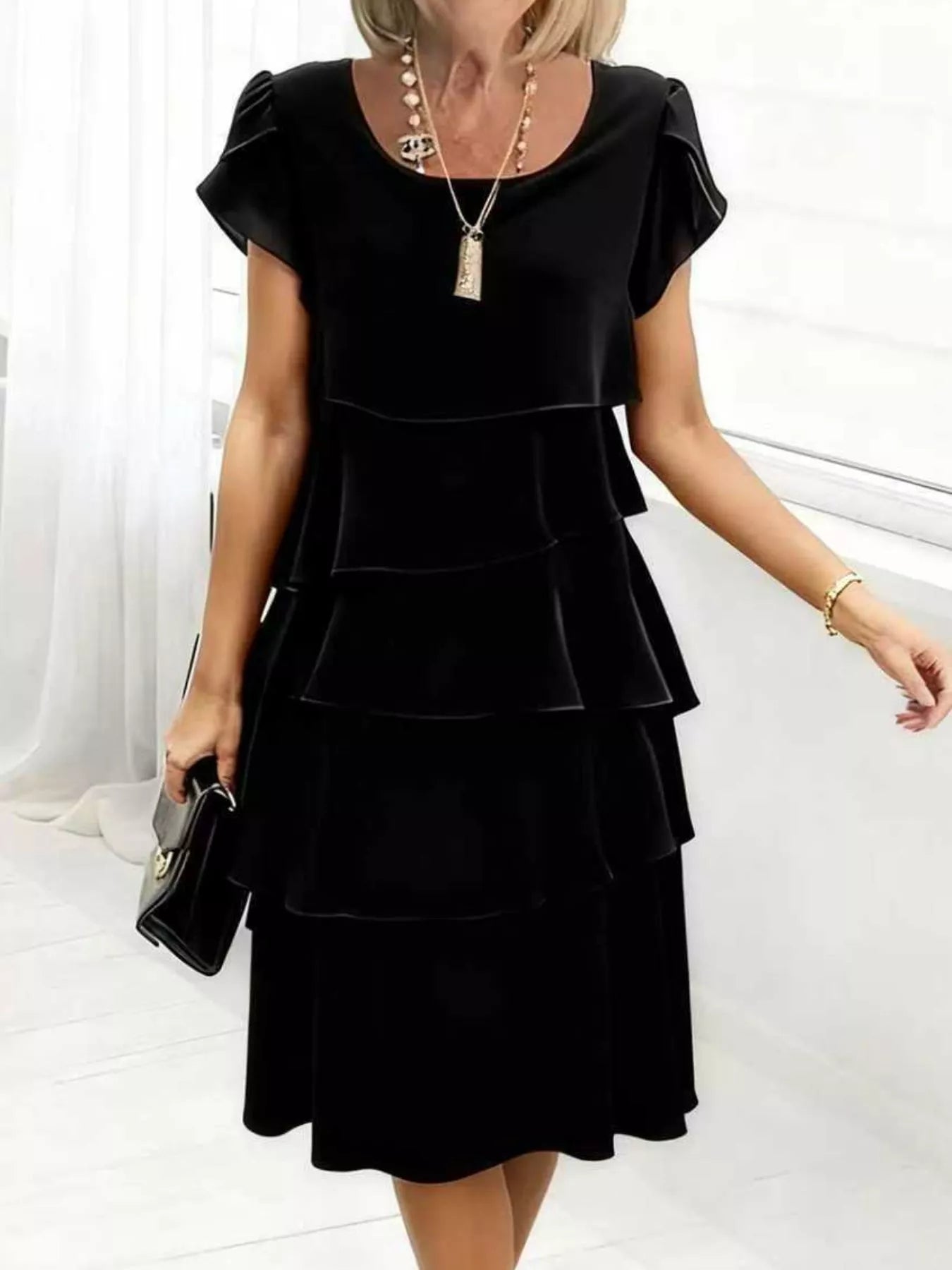 Woman wearing a black dress with ruffled layers against a white background