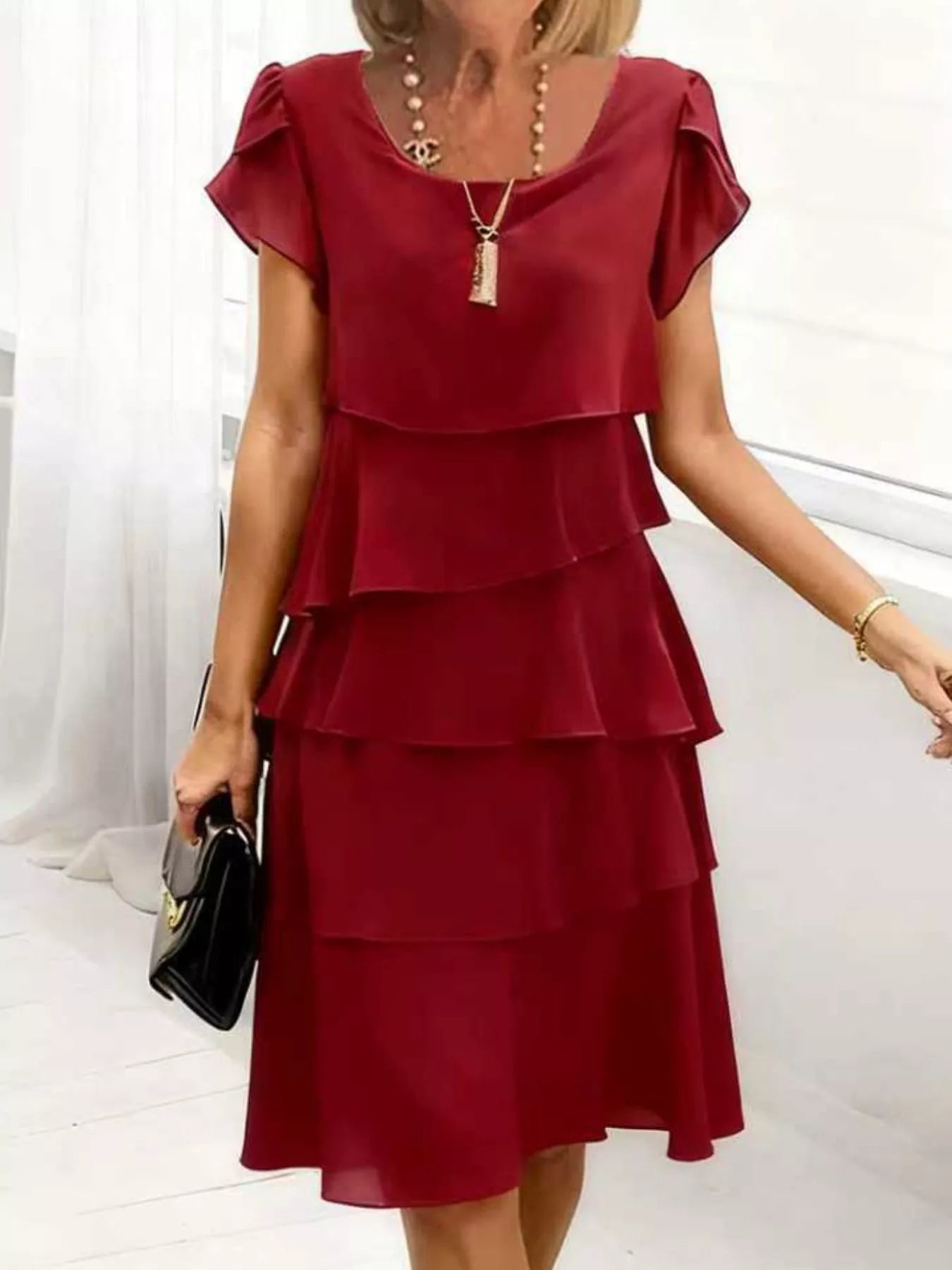 Burgundy tiered dress worn by a person on a white background