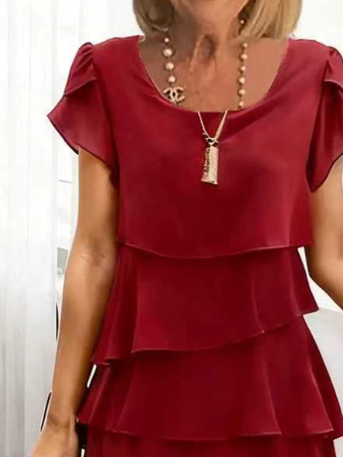 Burgundy layered dress worn by a person with a neutral background