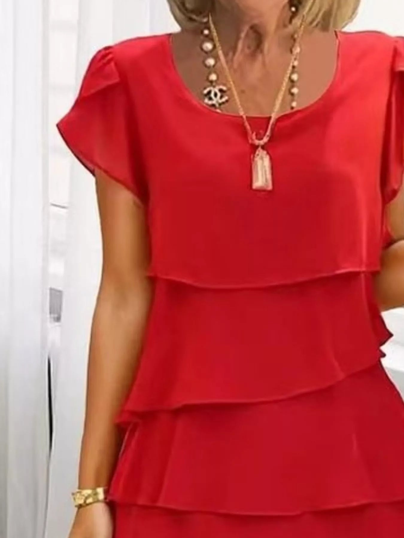 Scarlet layered dress worn by a person with a white background