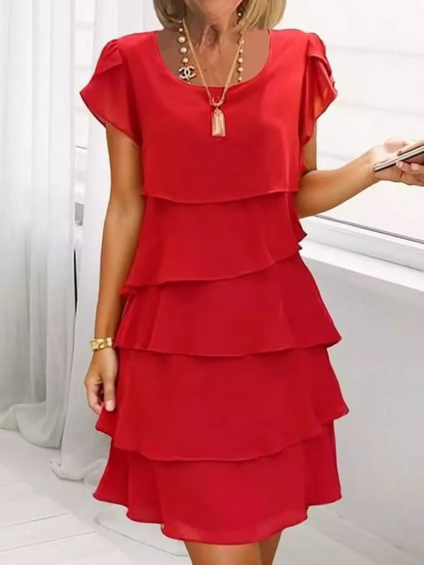 Scarlet tiered dress worn by a person on a white background