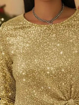Gold glittery top worn by a person with a blurred background