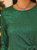 Green glittery top worn by a person with a blurred background