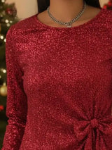 Red glittery dress with a knot detail worn by a person, with a blurred background.