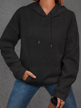 Person wearing a black hoodie with a textured pattern on a gray background