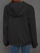 Person wearing a black jacket with 'YES' text on the back against a gray background