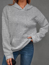 Person wearing a gray hoodie and blue jeans on a gray background