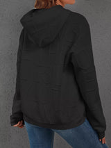 Person wearing a black jacket with branding on the back against a gray background