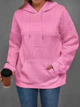 Person wearing a pink hoodie with 'LOVE' text, holding a coffee cup against a gray background