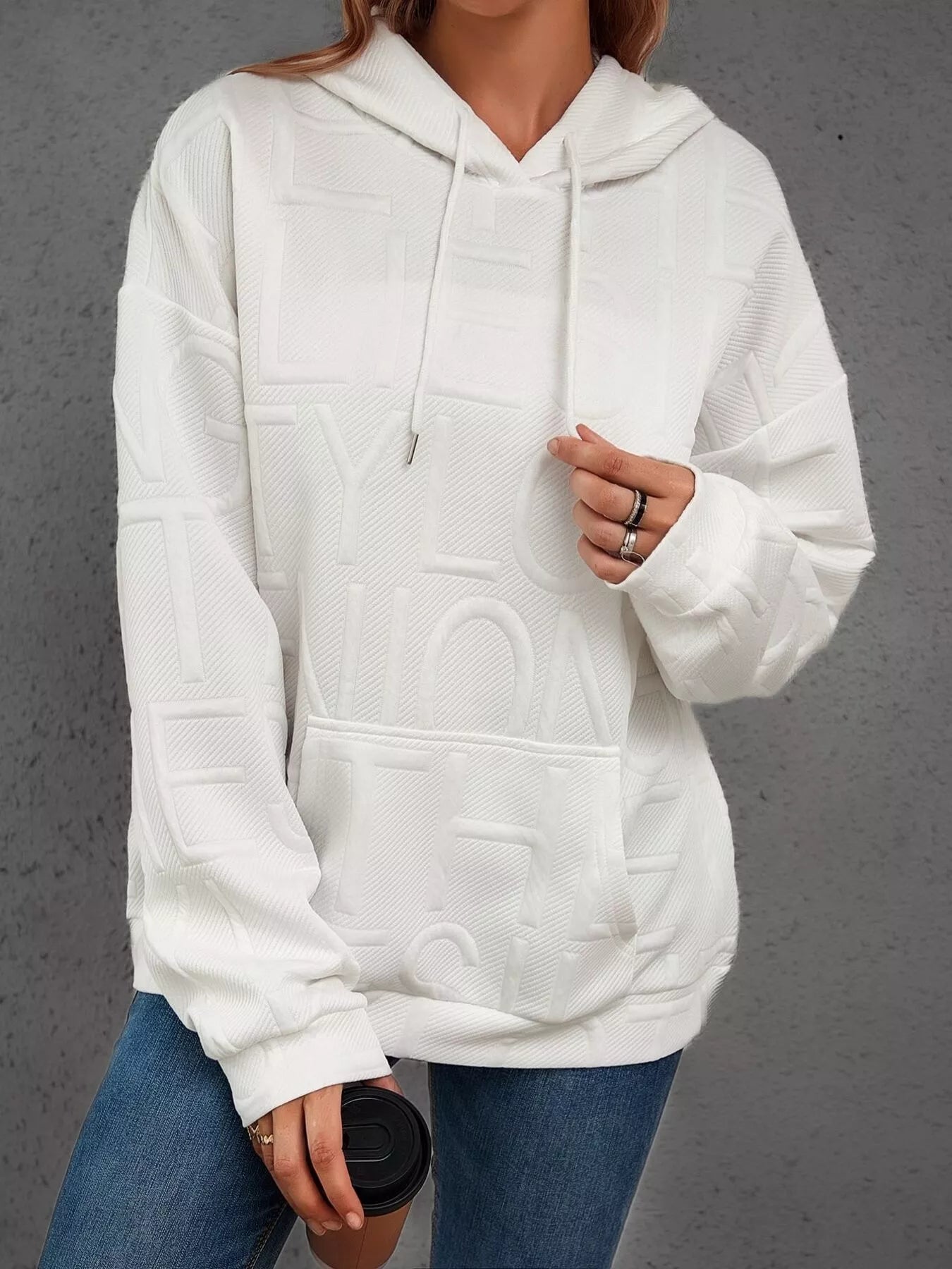Person wearing a white hoodie with geometric patterns on a gray background