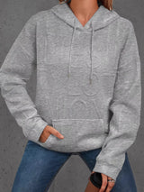 Person wearing a gray textured hoodie and blue jeans on a gray background