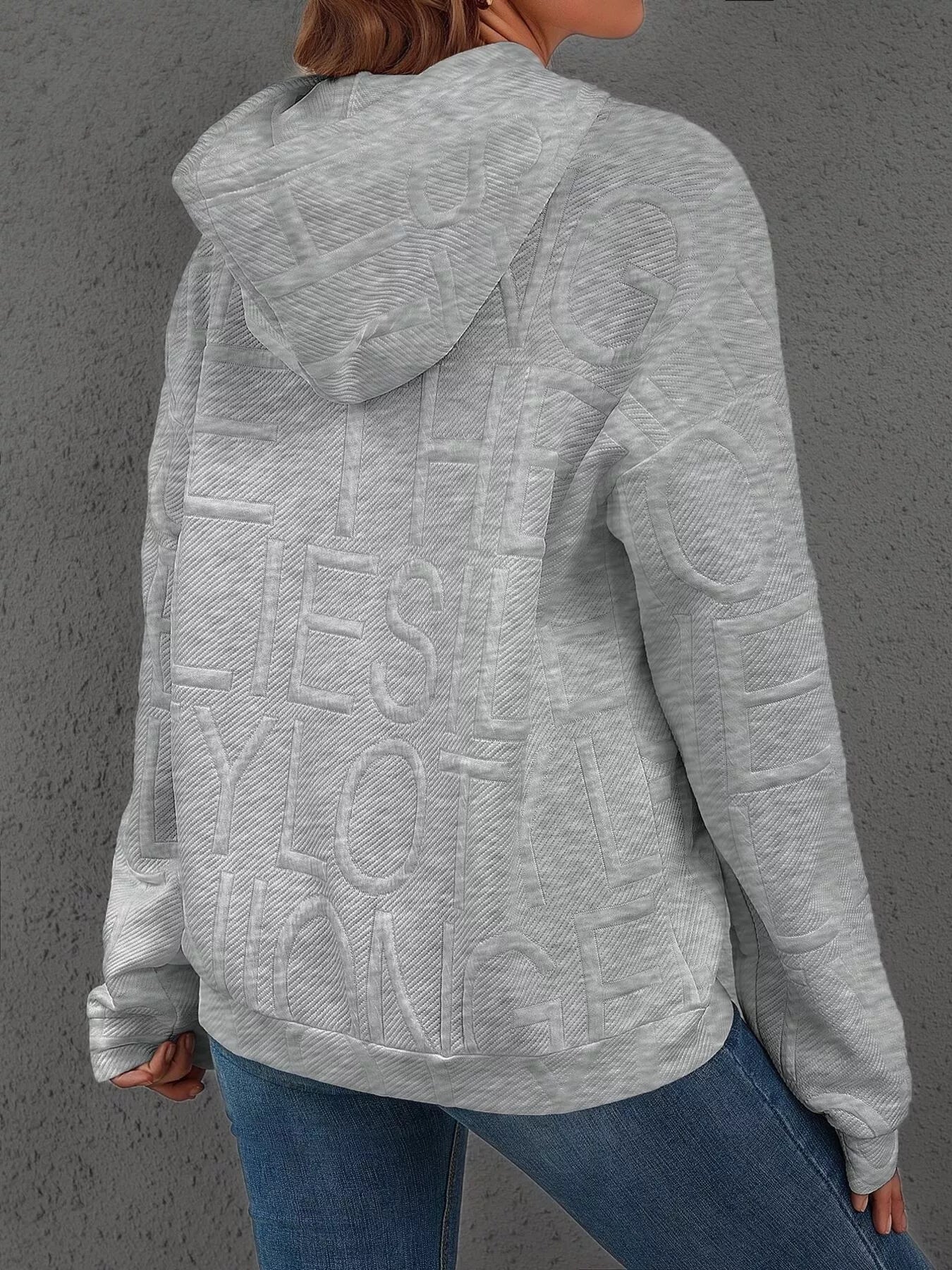 Person wearing a gray hoodie with text on the back against a gray background