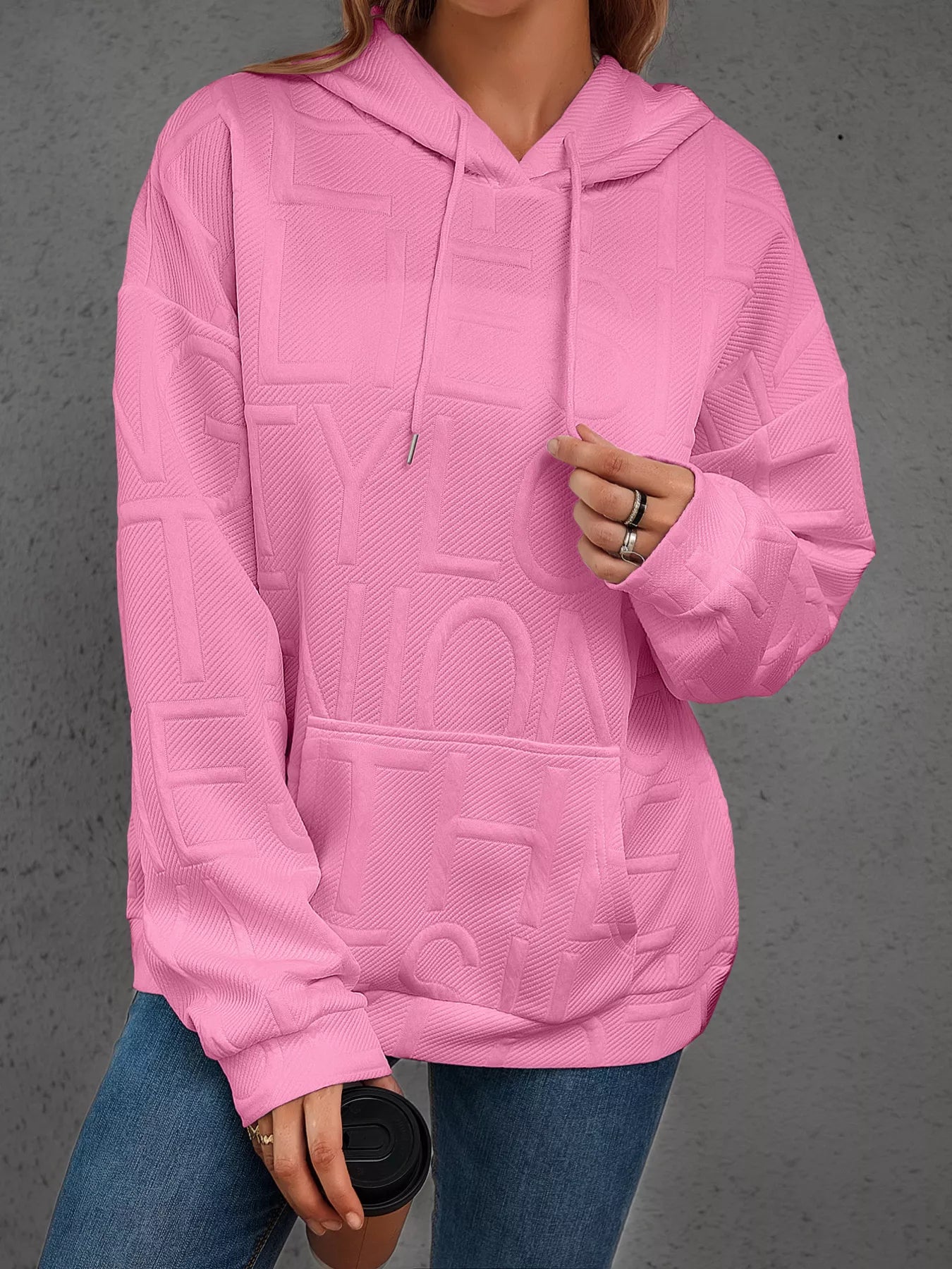 Person wearing a pink textured hoodie with a gray background