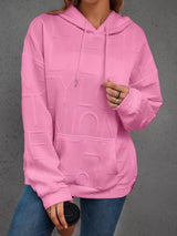 Person wearing a pink textured hoodie with a gray background