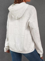 White hoodie with text pattern on the back worn by a person against a gray background