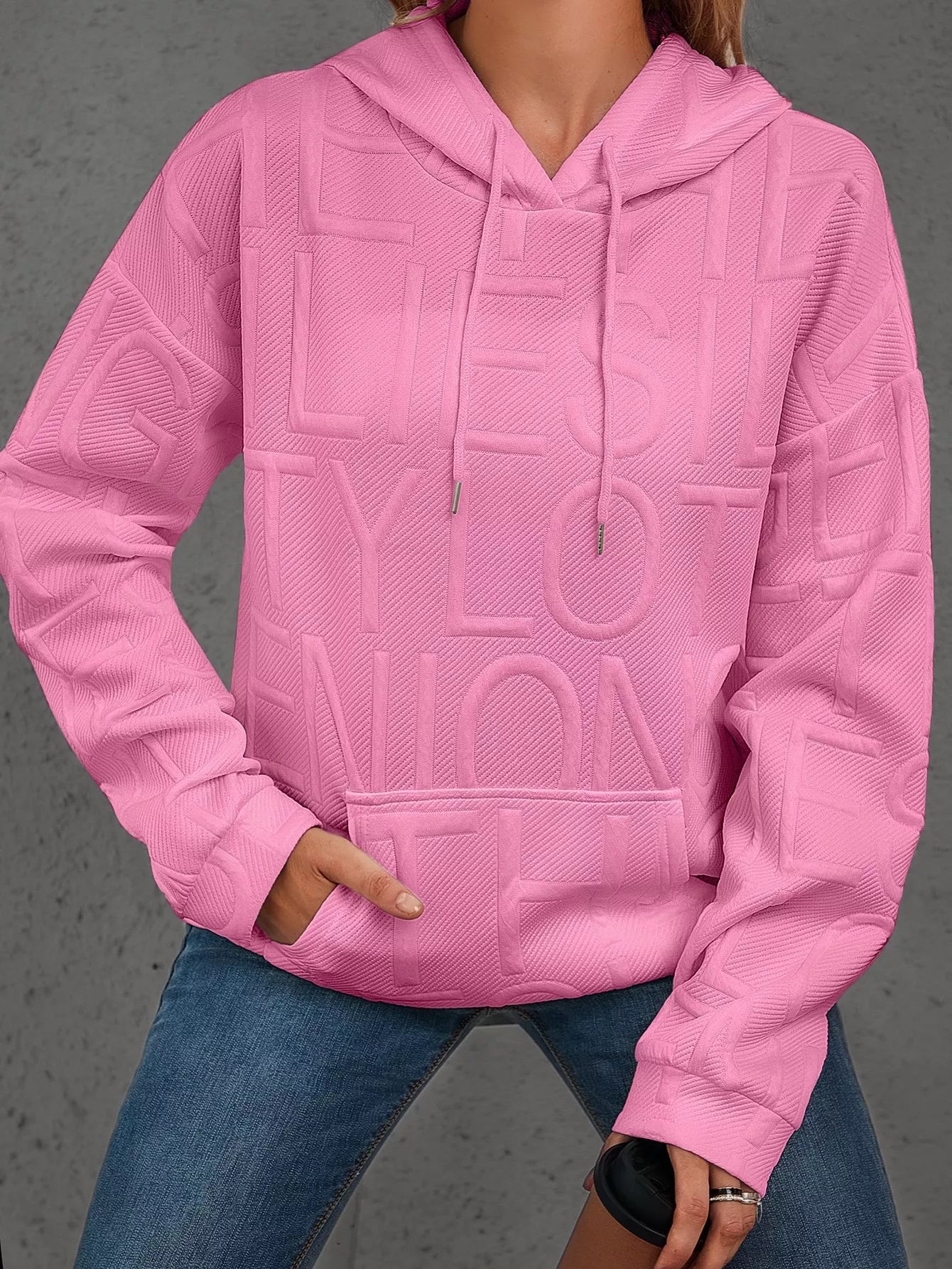 Person wearing a pink textured hoodie with text on a gray background