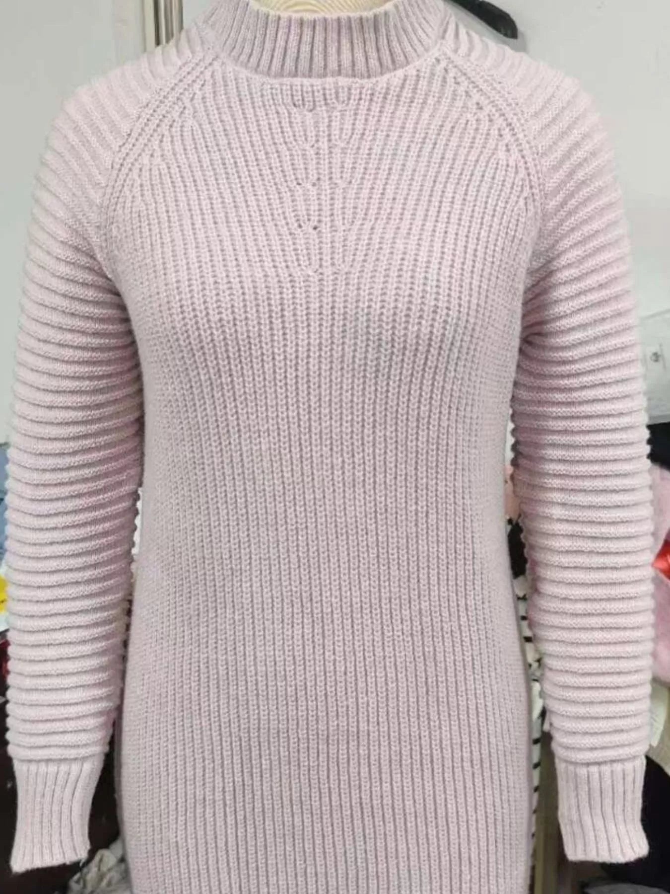 Woman wearing a dusty pink turtleneck raglan sleeve sweater dress paired with white knee-high boots and a white crossbody bag for a chic fall outfit.