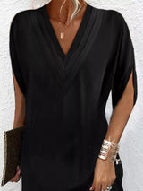 Person wearing a black dress with gold jewelry against a white background