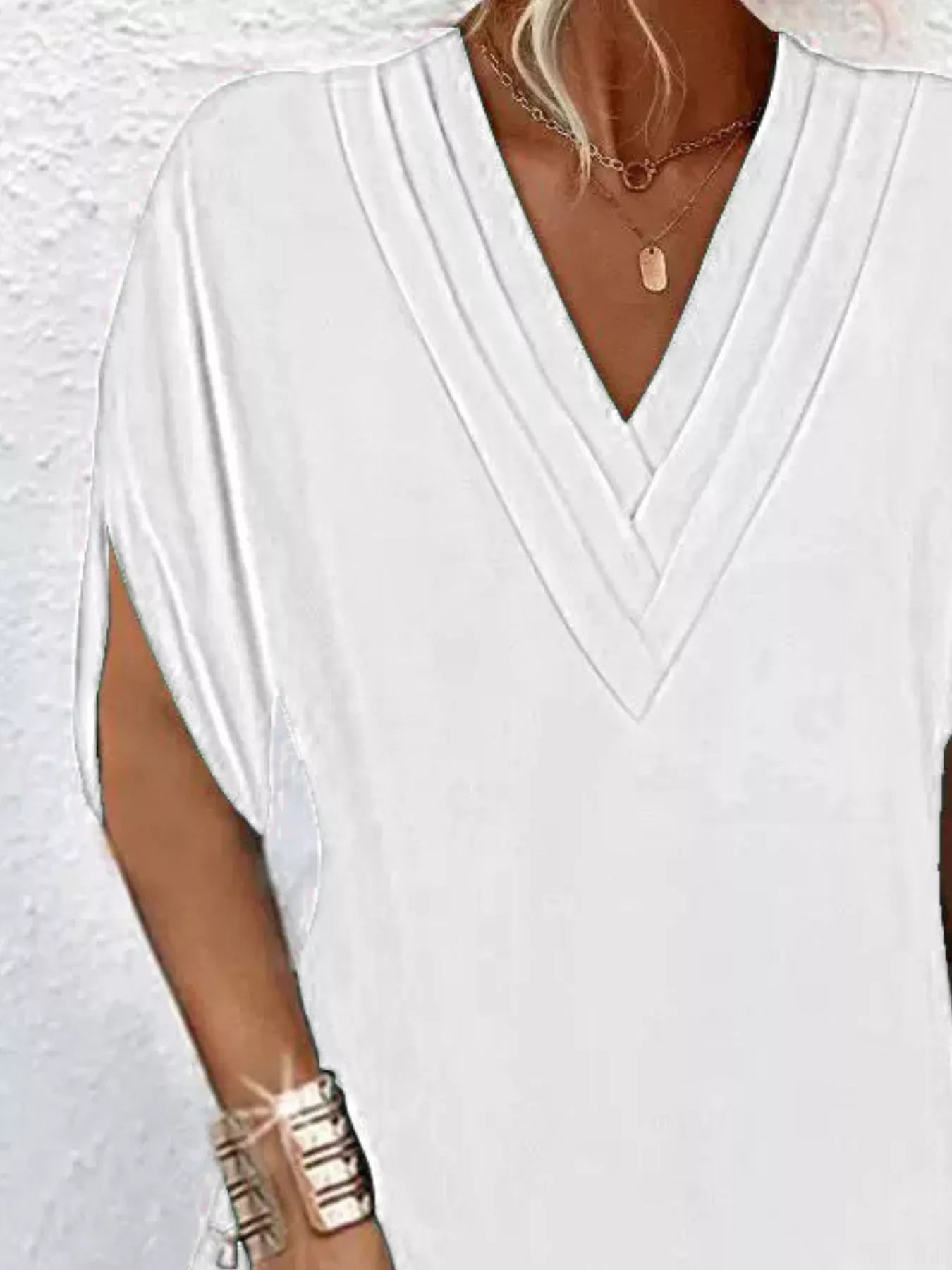 White top worn by a person with a plain background