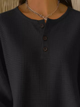 Dark textured shirt with a necklace on a neutral background