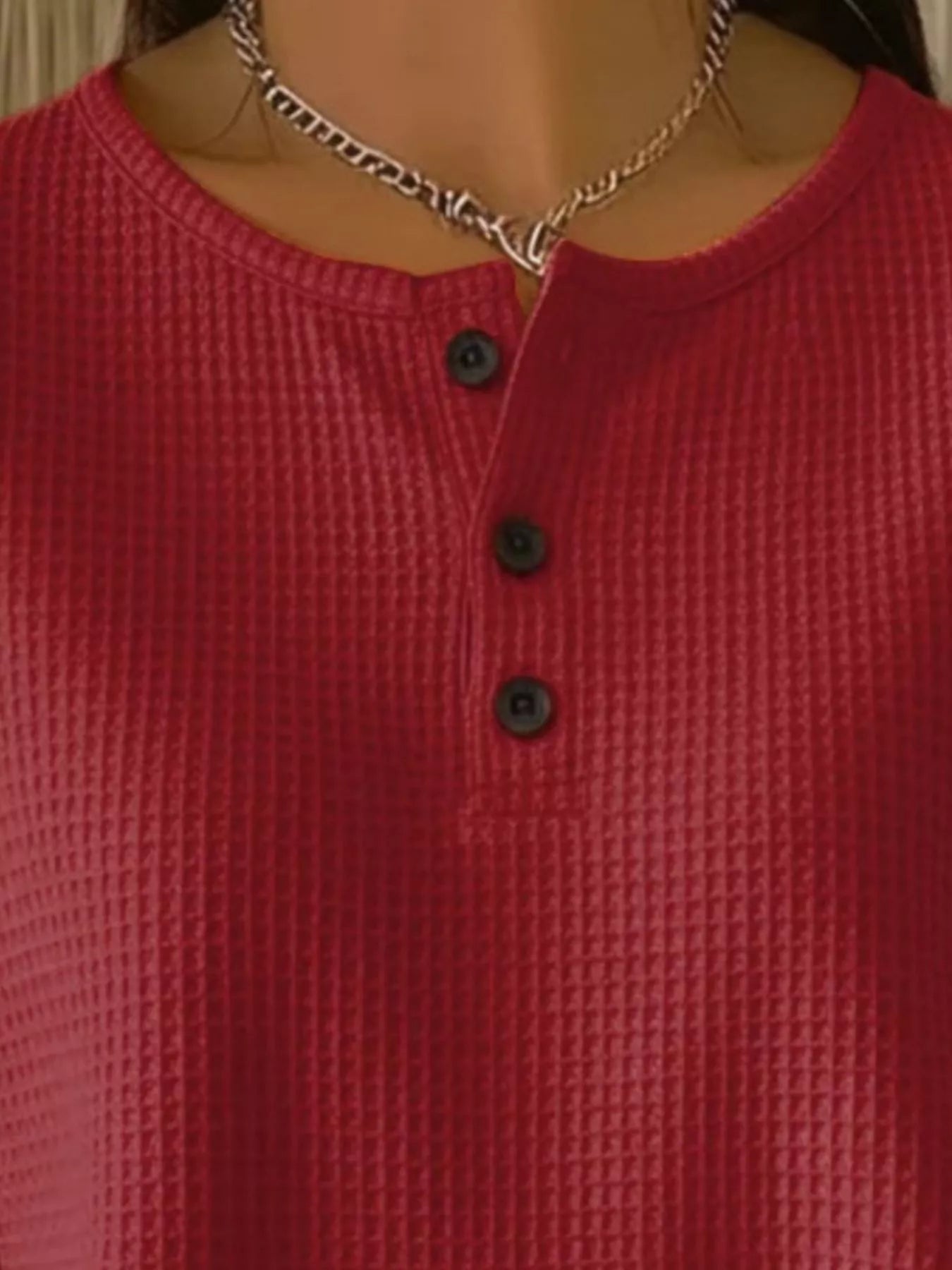 Red textured shirt with black buttons worn by a mannequin.