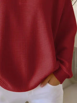 Red textured sweater worn by a person with a blurred background