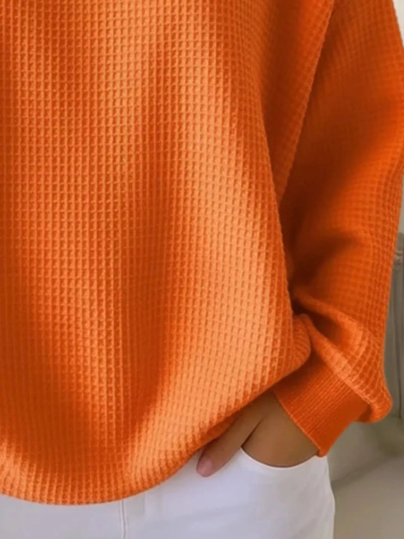 Close-up of an orange textured sweater with a blurred background