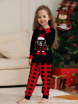 Girl wearing matching Christmas Crew graphic pajama sets with black long-sleeve tops and red buffalo plaid pants.