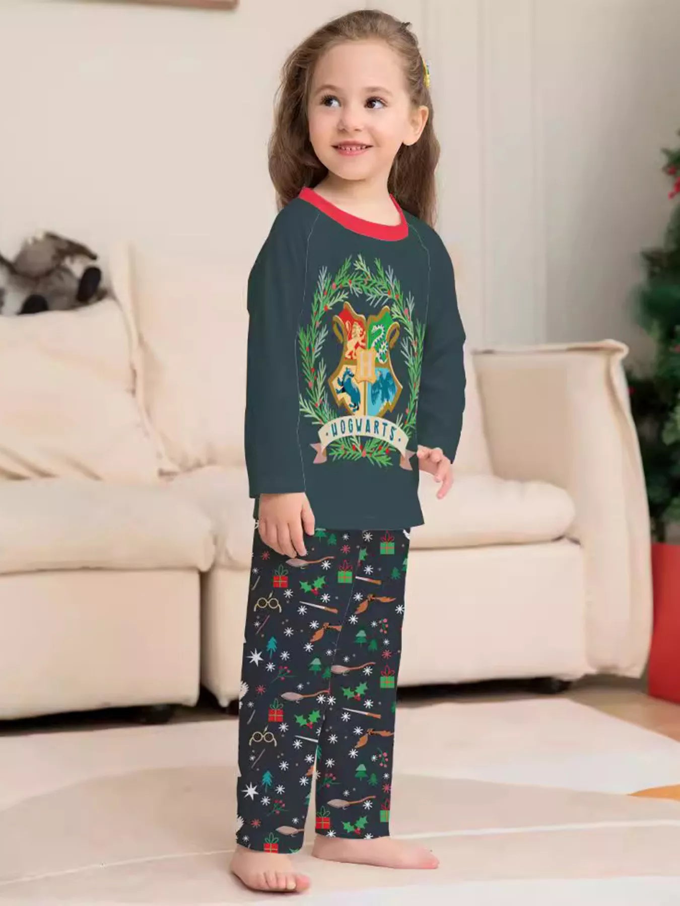 Family wearing matching dark green Hogwarts graphic Christmas pajama tops with coordinating navy holiday print pajama pants.