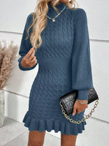 Woman wearing a gray blue cable-knit sweater mini dress with mock neckline, long sleeves, fitted waist and feminine ruffled hem.