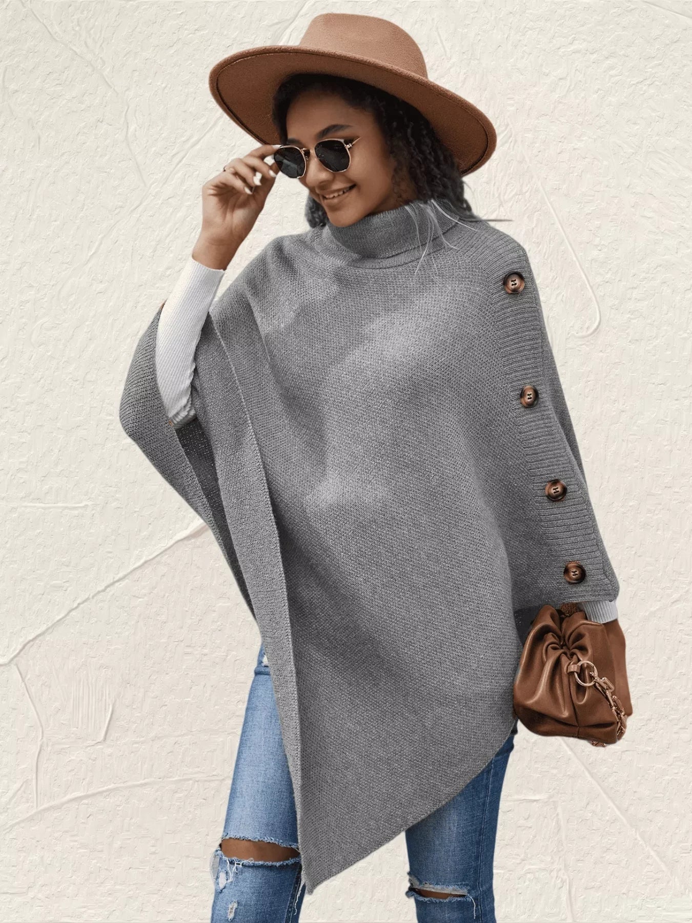 Women's gray turtleneck poncho pullover with decorative sleeve buttons and relaxed knit silhouette.