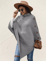 Women's gray turtleneck poncho pullover with decorative sleeve buttons and relaxed knit silhouette.