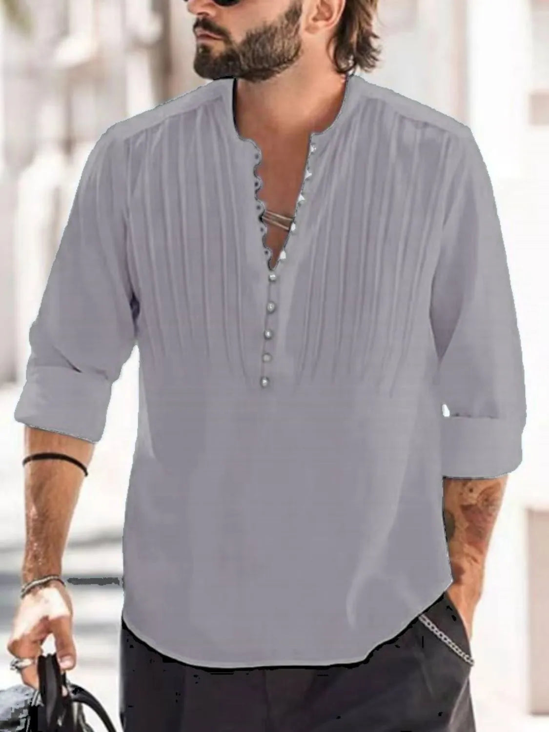 Man wearing a gray button-detail long sleeve cotton polo with rolled sleeves and black pants.
