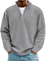 Man wearing a gray ribbed corduroy quarter zip pullover sweatshirt layered over a white shirt.