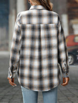 Woman wearing a gray plaid oversized button-up shirt layered over a white top with jeans.