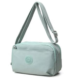 Small green nylon crossbody bag with an adjustable matching strap, silver-tone buckle, zippered top closure, and front pocket detail.