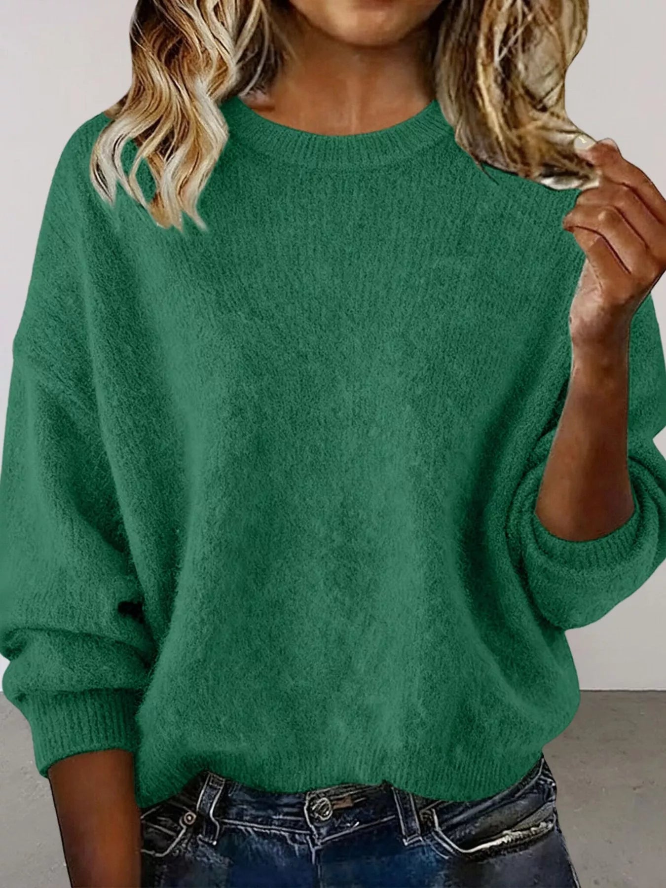 Woman wearing a green round neck dropped shoulder sweater with dark-wash jeans.