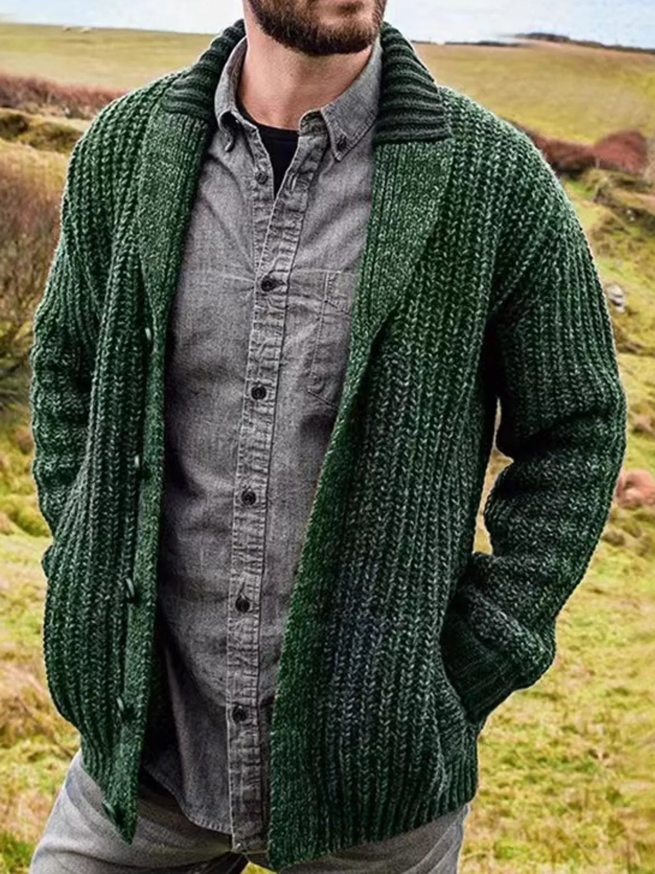 Men's green chunky knit shawl collar cardigan with button-front closure, ribbed texture, and front pockets, layered over a gray button-down shirt.