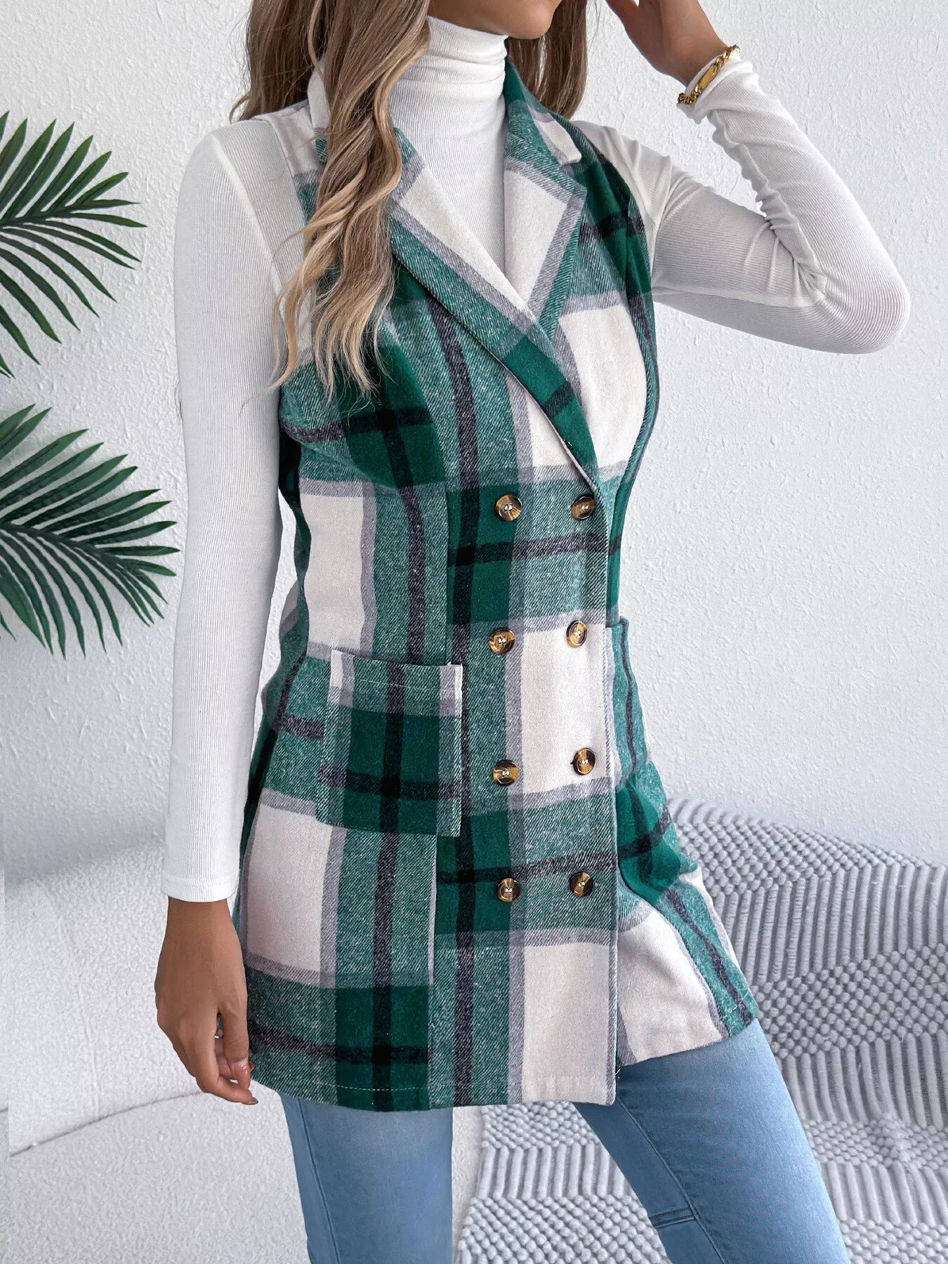 Women’s green plaid double-breasted long vest coat with pockets styled over a white turtleneck and jeans.