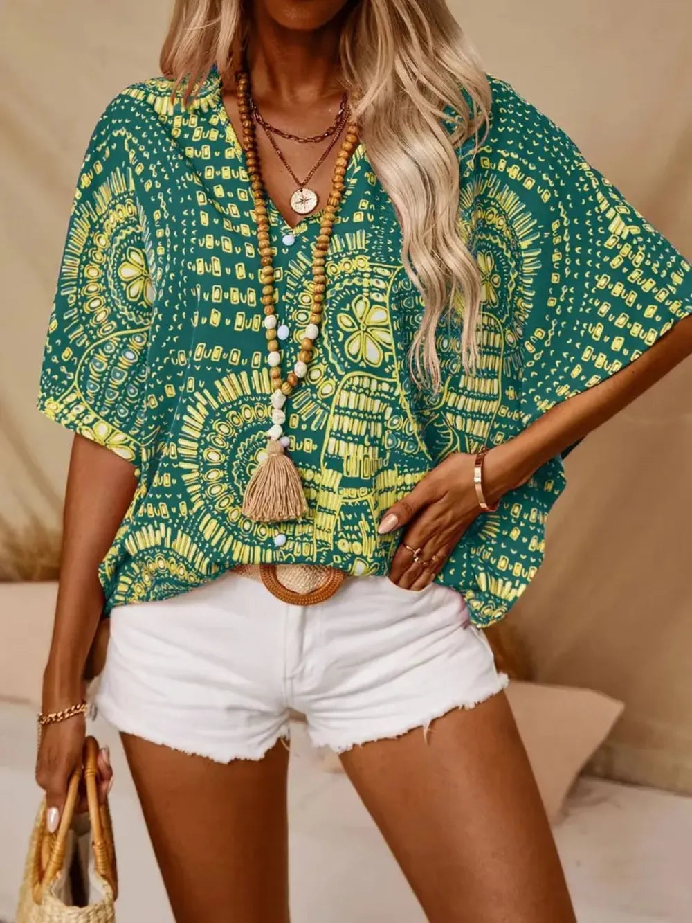 Green printed V-neck top with half sleeves and a relaxed boho-inspired fit paired with white shorts.