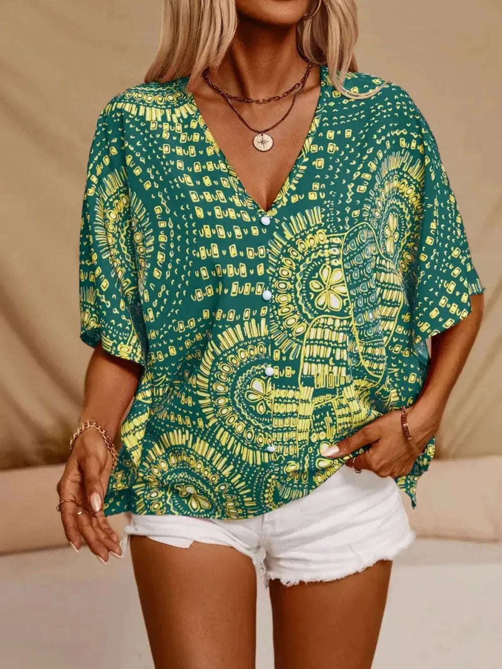 Green printed V-neck top with half sleeves and a relaxed boho-inspired fit paired with white shorts.
