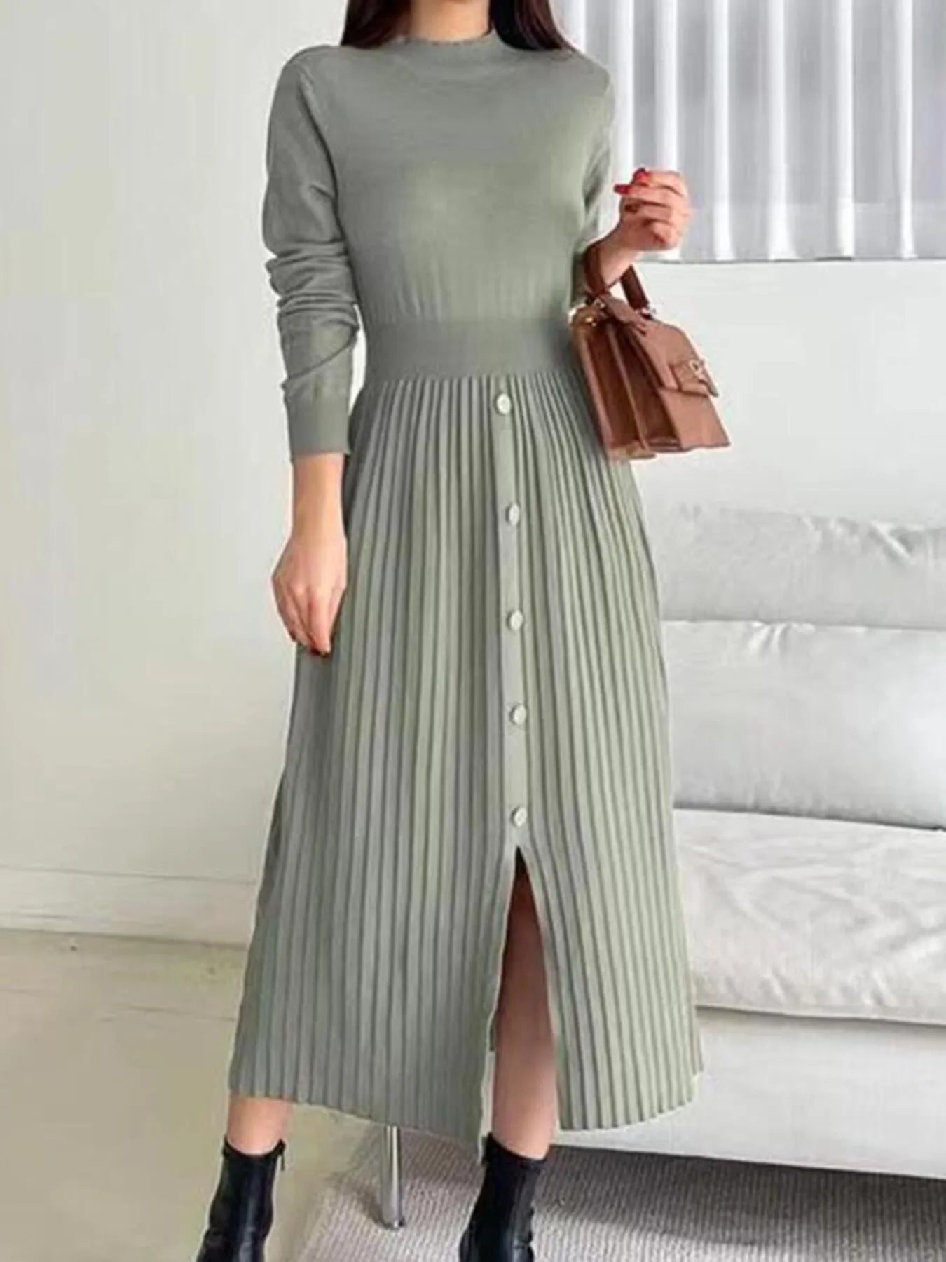 Woman wearing a green mock neck long sleeve knit midi dress with pleated skirt, front buttons and slit.